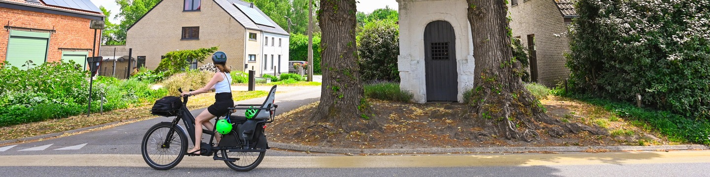 Fietser voor de lindenbomen in de Drielindenstraat aan de zestiende eeuwse kapel.